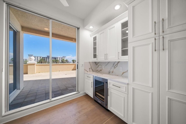 kitchen with backsplash, glass insert cabinets, white cabinets, wood finished floors, and beverage cooler