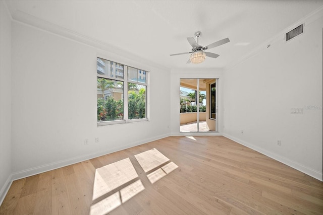 empty room with light wood-type flooring, baseboards, visible vents, and ornamental molding