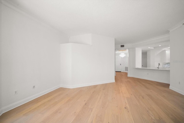 unfurnished living room with light wood-type flooring, visible vents, baseboards, and a sink