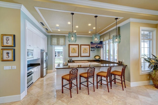 kitchen with a healthy amount of sunlight, appliances with stainless steel finishes, a kitchen breakfast bar, and ornamental molding