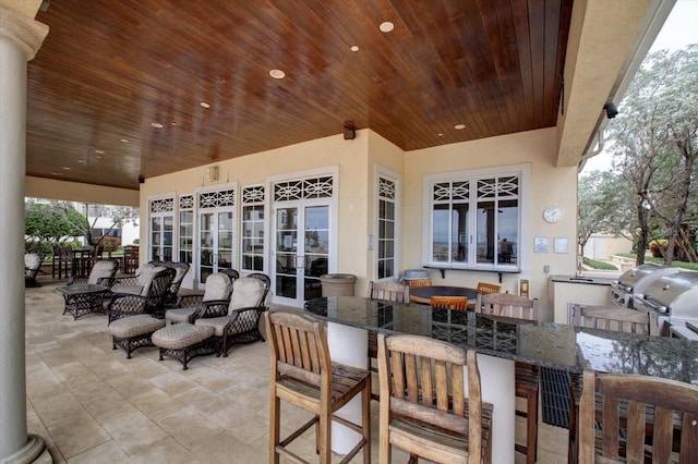 view of patio featuring outdoor wet bar, area for grilling, and french doors