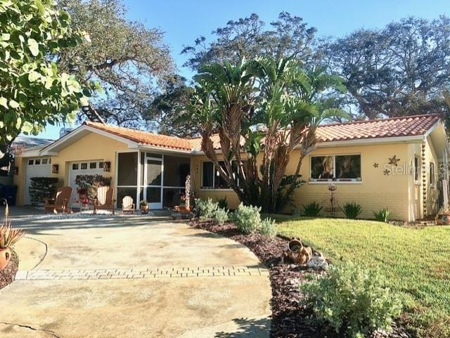 view of front of property featuring concrete driveway, a tile roof, an attached garage, a front yard, and stucco siding