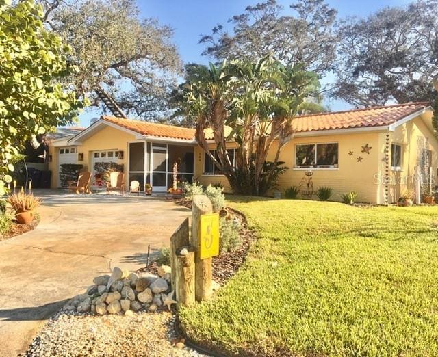 view of front of home featuring driveway, a tile roof, an attached garage, a front yard, and stucco siding