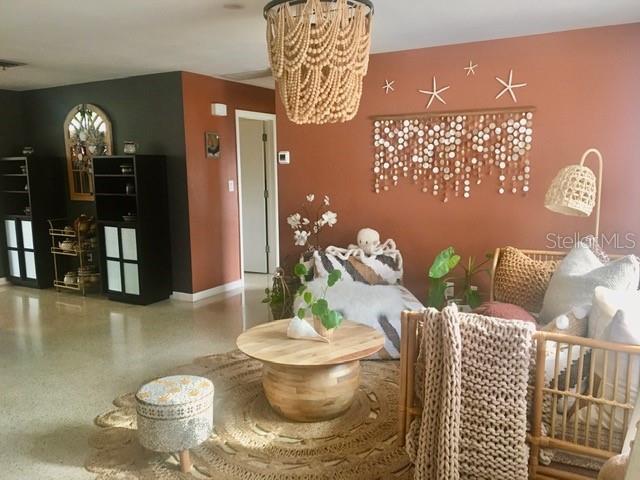 interior space with baseboards, a notable chandelier, and speckled floor