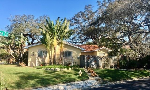 view of front of house featuring fence, a front lawn, and stucco siding