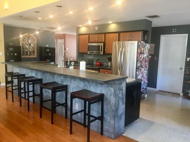 kitchen featuring stainless steel appliances, dark countertops, visible vents, and tasteful backsplash