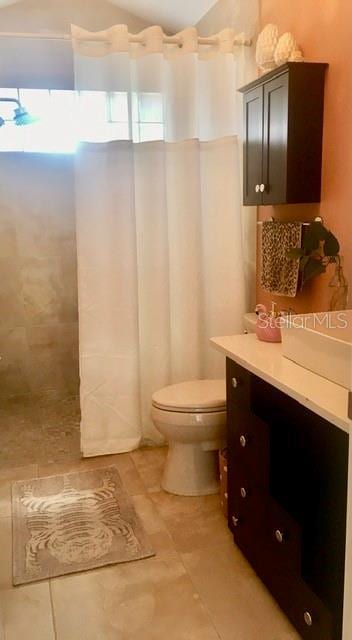 full bath with a shower with shower curtain, vanity, toilet, and tile patterned floors