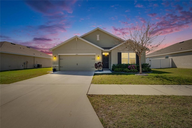 view of front facade with concrete driveway, central AC, an attached garage, and a lawn