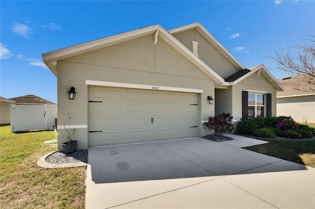 single story home with a garage, a front yard, concrete driveway, and stucco siding