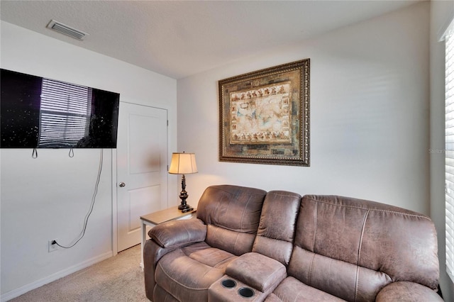 living area featuring baseboards, visible vents, and light colored carpet