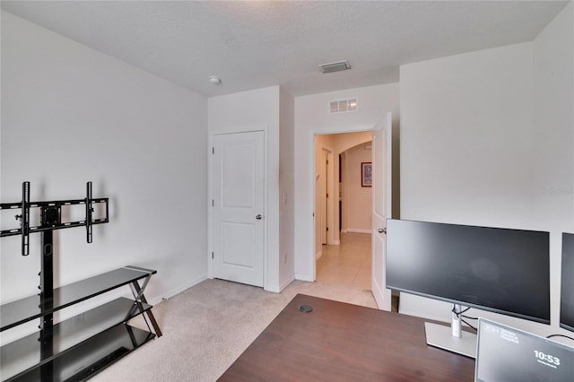 home office with arched walkways, light carpet, visible vents, and baseboards