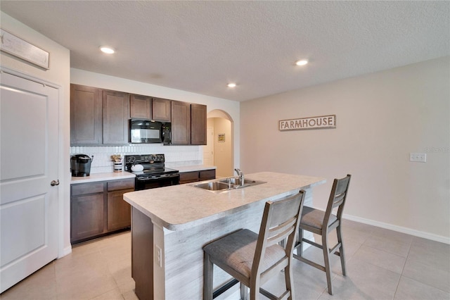 kitchen featuring arched walkways, tasteful backsplash, a sink, black appliances, and a kitchen breakfast bar