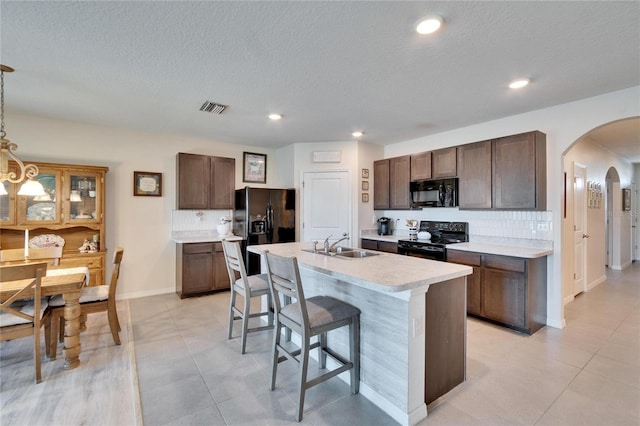 kitchen featuring arched walkways, a sink, visible vents, light countertops, and black appliances