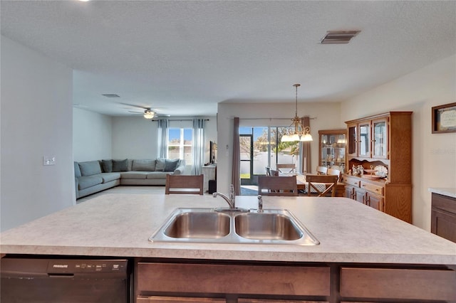 kitchen featuring a sink, visible vents, black dishwasher, light countertops, and decorative light fixtures