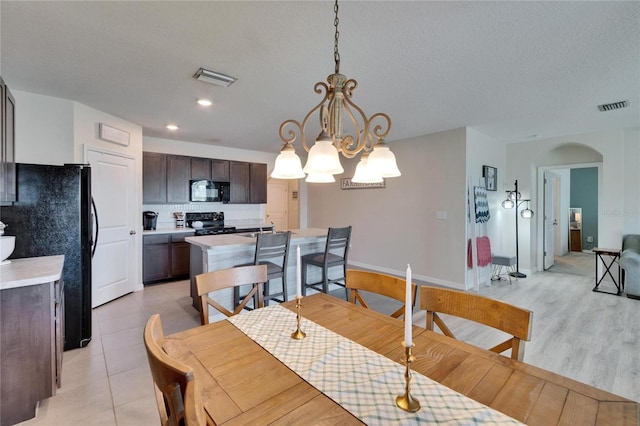 dining space featuring a chandelier, arched walkways, visible vents, and a textured ceiling