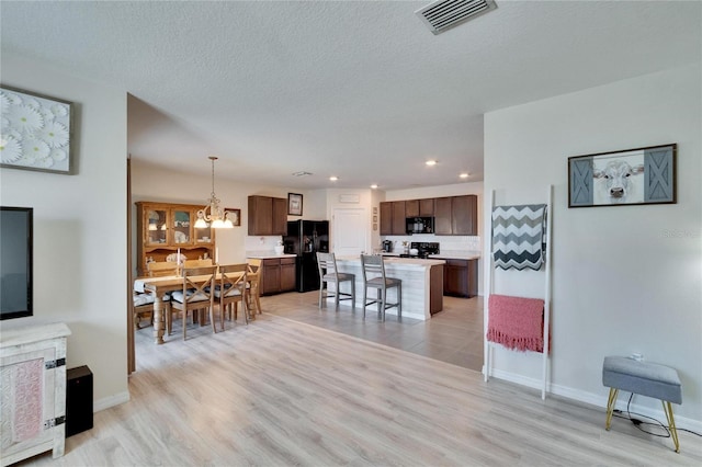 interior space featuring visible vents, baseboards, light wood-style flooring, a textured ceiling, and recessed lighting