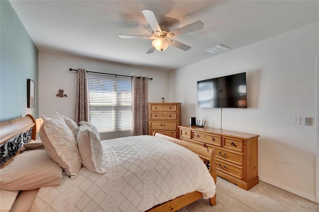 bedroom featuring visible vents, light carpet, ceiling fan, a textured ceiling, and baseboards