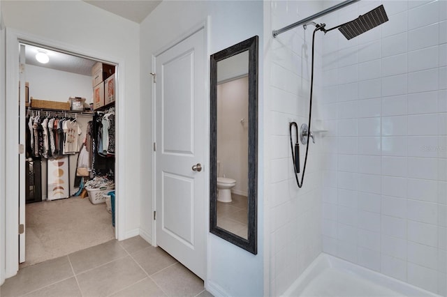 full bathroom featuring a stall shower, tile patterned flooring, a spacious closet, and toilet