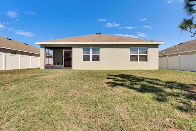 back of house with a sunroom, a fenced backyard, stucco siding, and a yard