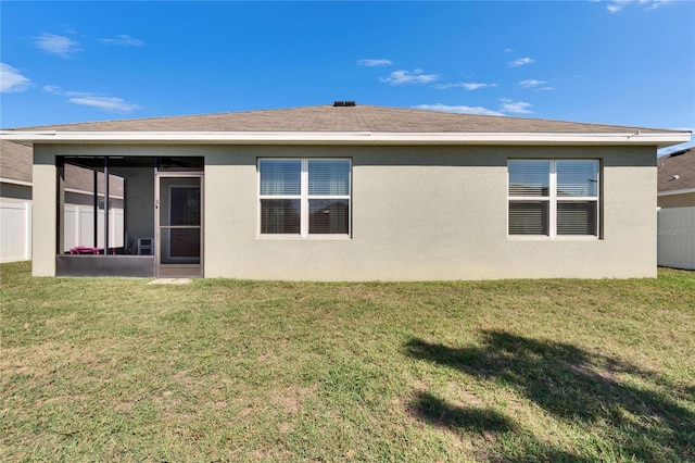 rear view of property with a sunroom, fence, stucco siding, and a yard