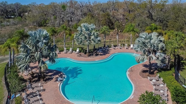 pool featuring a forest view, a patio area, and fence