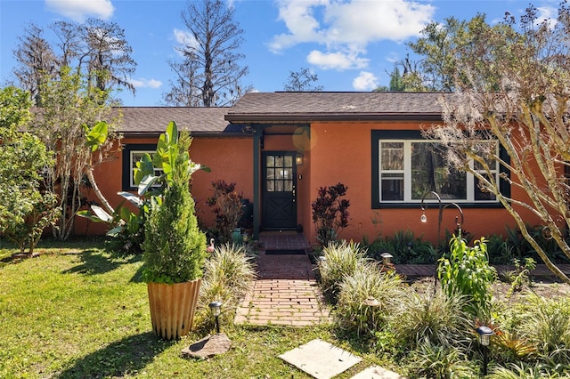 view of front of home with stucco siding and a front yard