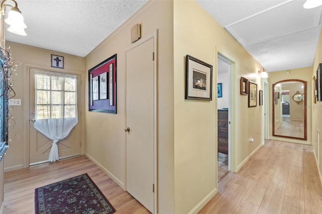 entryway featuring light wood-style floors, baseboards, arched walkways, and a textured ceiling