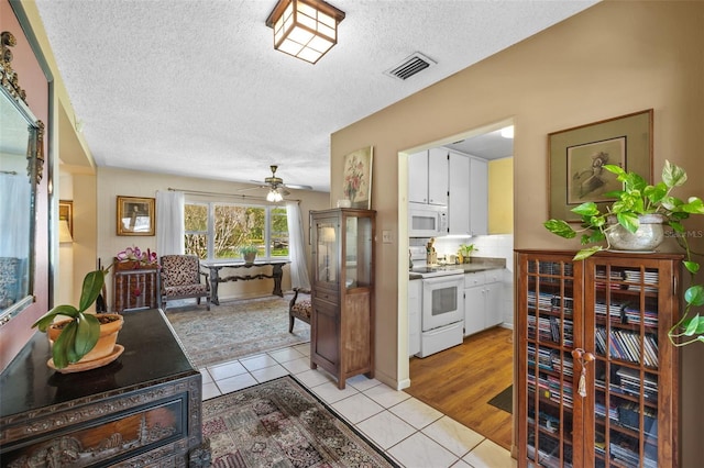 interior space with visible vents, decorative backsplash, white cabinets, light tile patterned flooring, and white appliances