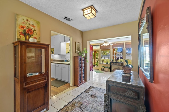 interior space with light tile patterned floors, a textured ceiling, visible vents, and a sink