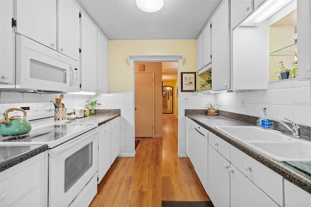 kitchen with white appliances, a sink, white cabinetry, light wood-style floors, and dark countertops