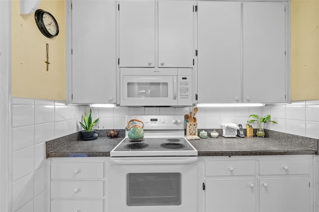 kitchen featuring dark countertops, white appliances, white cabinets, and decorative backsplash