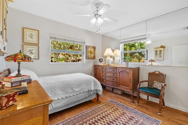 bedroom with ceiling fan, wood finished floors, visible vents, and baseboards