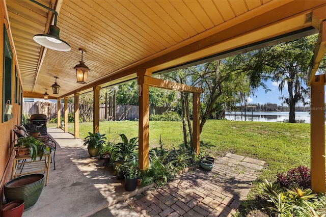 view of patio / terrace with a water view and fence