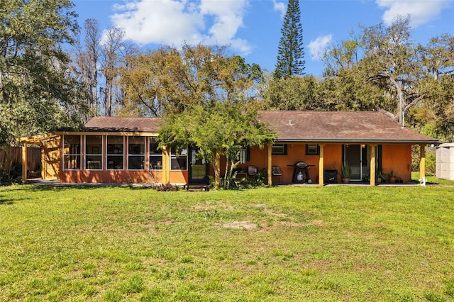 rear view of property featuring a lawn and a sunroom