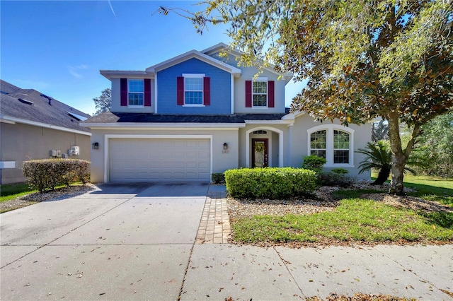 traditional home with driveway, an attached garage, and stucco siding