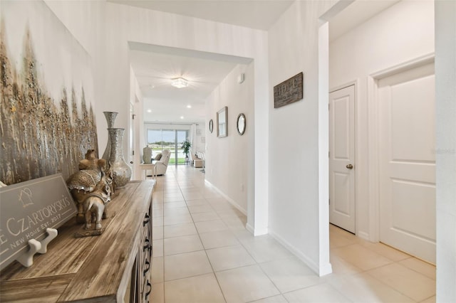 hall featuring light tile patterned floors and baseboards