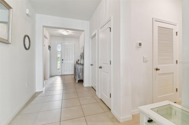 hallway featuring baseboards and light tile patterned flooring