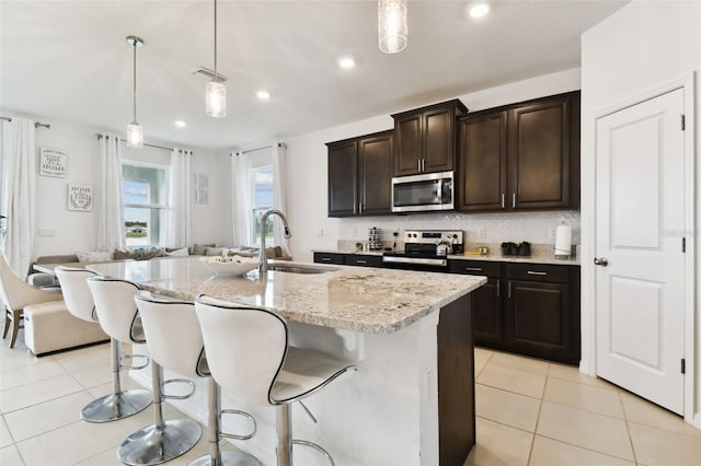 kitchen featuring stainless steel appliances, light tile patterned flooring, a sink, and decorative backsplash