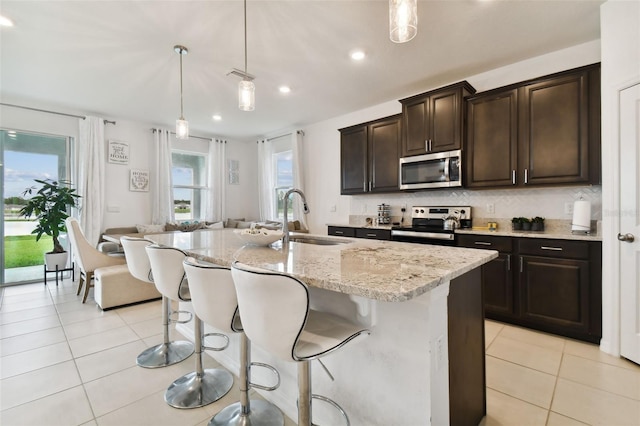 kitchen with light tile patterned floors, decorative backsplash, stainless steel appliances, and a sink