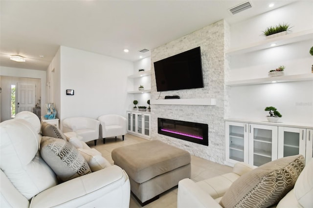 living room featuring a stone fireplace, recessed lighting, visible vents, and built in features