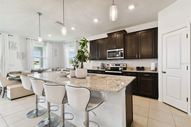 kitchen with light stone counters, a breakfast bar area, stainless steel appliances, tasteful backsplash, and light tile patterned flooring