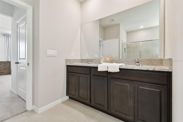 bathroom with double vanity, a stall shower, baseboards, visible vents, and a sink