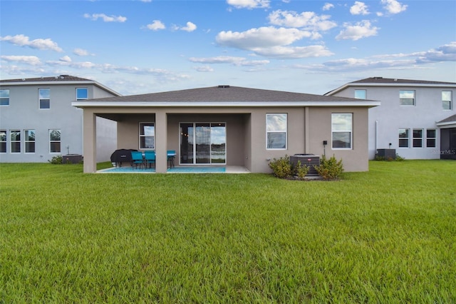 rear view of house with a lawn, a patio area, cooling unit, and stucco siding