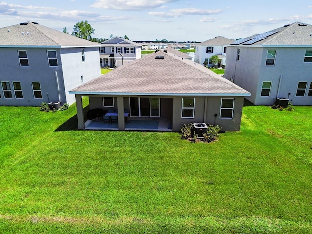 back of property with a yard, central air condition unit, a shingled roof, a patio area, and a residential view