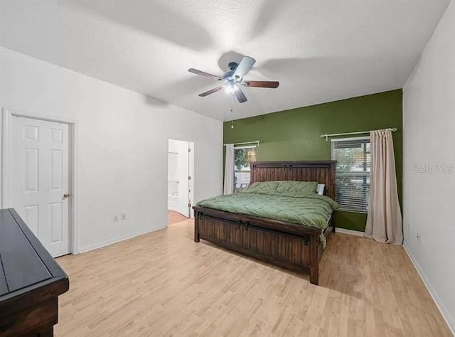 bedroom featuring connected bathroom, ceiling fan, light wood-style flooring, and baseboards