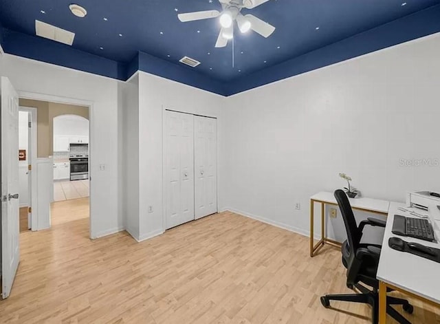 office space featuring arched walkways, visible vents, a ceiling fan, light wood-type flooring, and baseboards