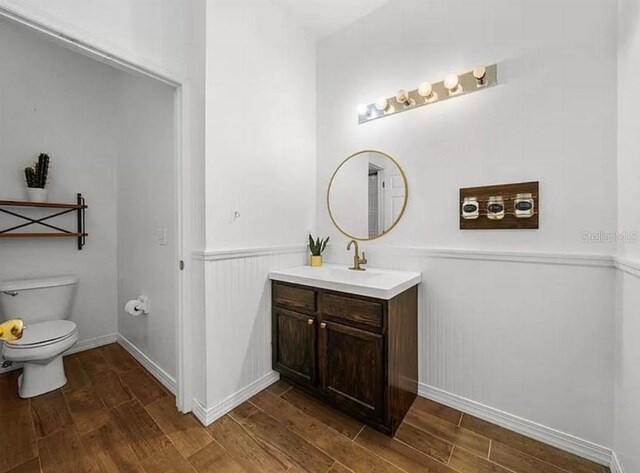 bathroom with toilet, wainscoting, wood finished floors, and vanity