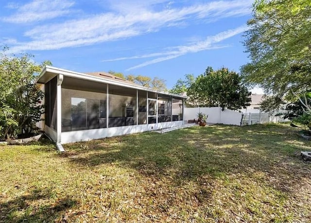 back of property featuring a sunroom, fence, and a lawn