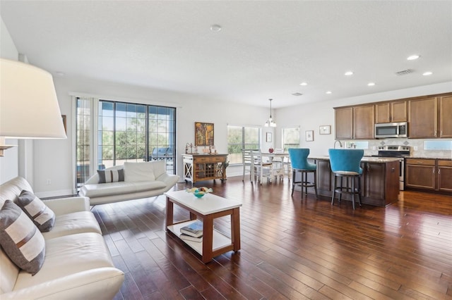 living area featuring baseboards, dark wood-type flooring, visible vents, and recessed lighting