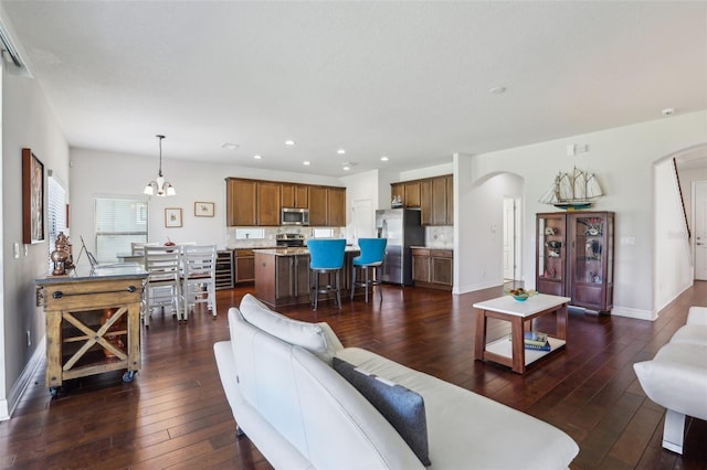 living area featuring baseboards, arched walkways, dark wood-type flooring, and recessed lighting